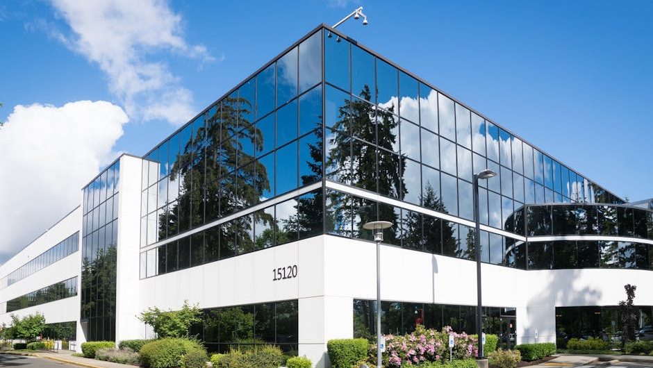 Contemporary office building in Redmond with reflective glass and lush greenery, captured on a sunny day.